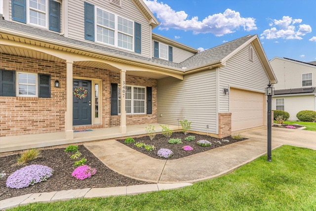 entrance to property with roof with shingles, brick siding, an attached garage, driveway, and a porch