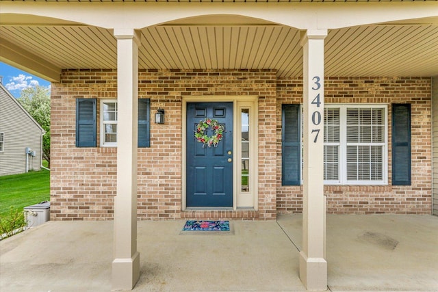 entrance to property with a porch and brick siding