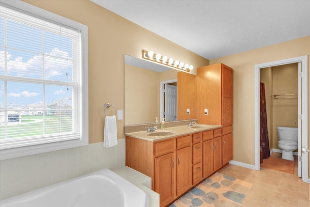 bathroom featuring a tub, a sink, a healthy amount of sunlight, and toilet