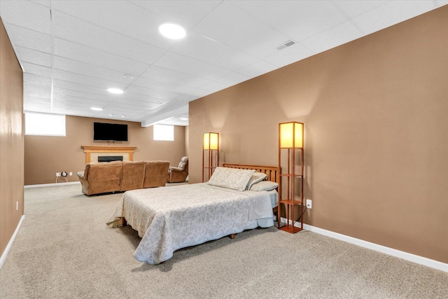 carpeted bedroom with baseboards, visible vents, multiple windows, and a fireplace