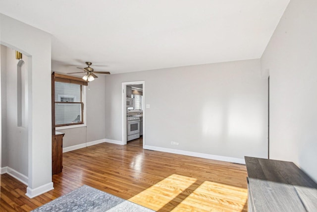 unfurnished living room featuring baseboards, ceiling fan, and light wood-style floors