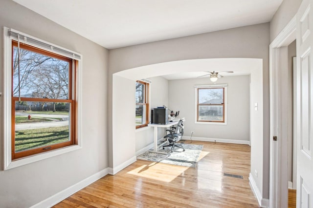 home office with baseboards, visible vents, arched walkways, and wood-type flooring