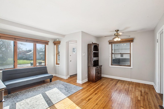 unfurnished room with arched walkways, baseboards, light wood-style floors, and a ceiling fan