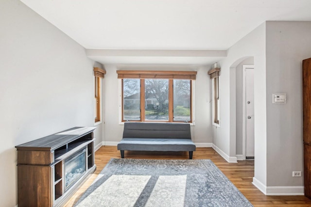 sitting room with baseboards, wood finished floors, and arched walkways