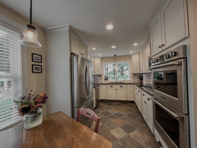 kitchen featuring decorative backsplash, pendant lighting, dark countertops, a sink, and stainless steel appliances