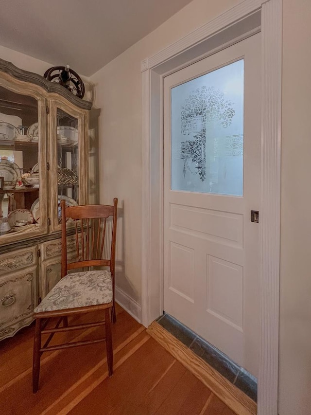 doorway to outside featuring baseboards and dark wood-style flooring