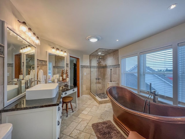 bathroom featuring double vanity, stone tile floors, a freestanding bath, a sink, and a stall shower