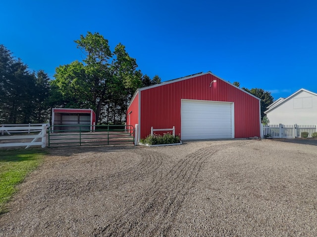 detached garage featuring fence and driveway