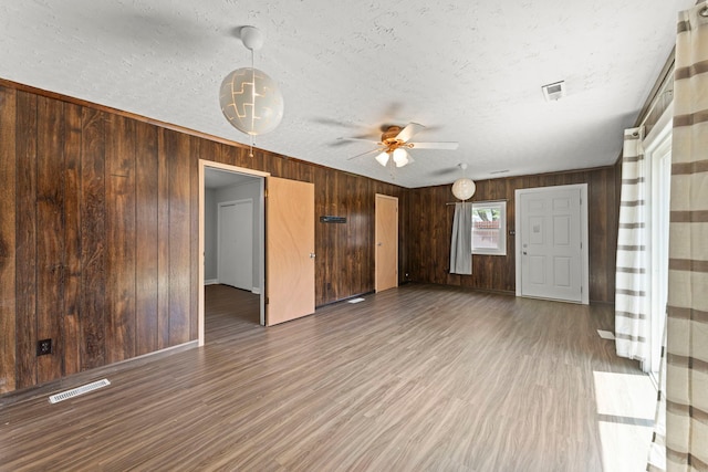 120 Anderson Ave, Joliet, IL 60433 - unfurnished living room with wood walls, ceiling fan, wood finished floors, a textured ceiling, and baseboards