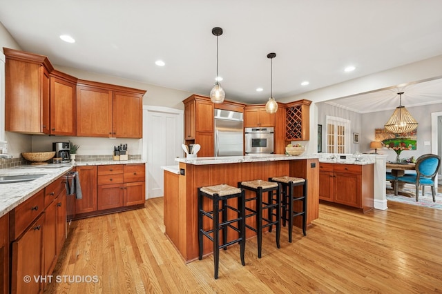 kitchen featuring light wood-type flooring, a kitchen island, appliances with stainless steel finishes, and brown cabinetry