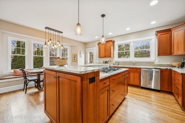 kitchen with light wood-style floors, decorative light fixtures, a kitchen island, and stainless steel appliances