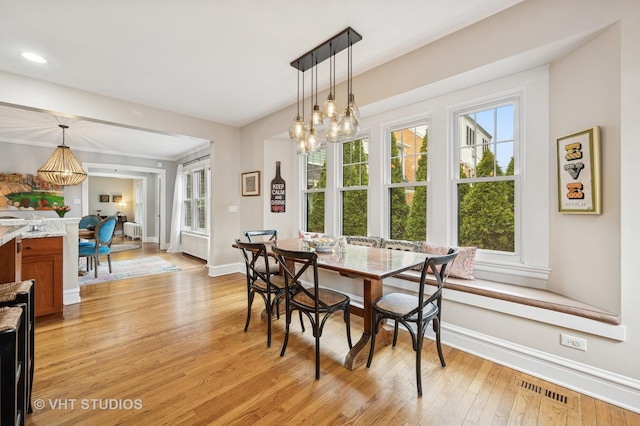 dining area with baseboards, a chandelier, light wood-style floors, and visible vents