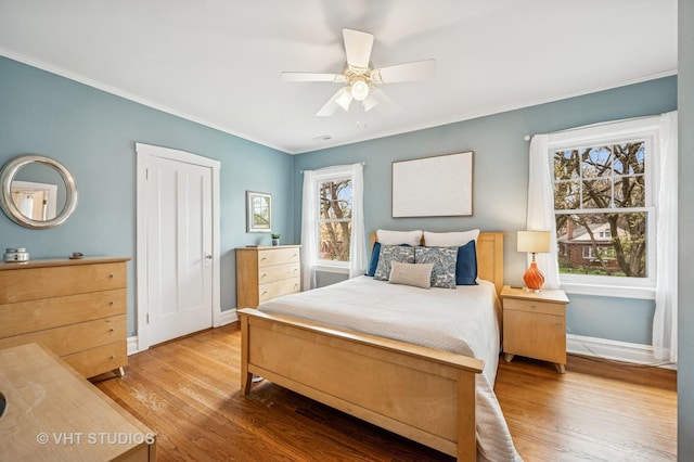 bedroom featuring wood finished floors, baseboards, ornamental molding, and a ceiling fan
