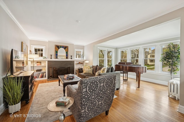 living area with radiator, crown molding, a brick fireplace, and wood finished floors