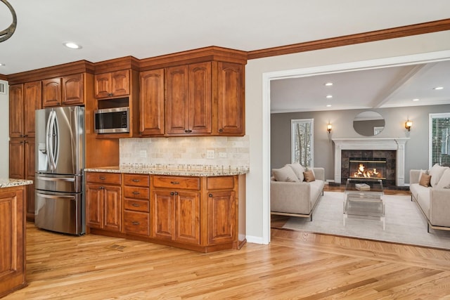 1019 Rockland Rd, Lake Bluff, IL 60044 - kitchen featuring appliances with stainless steel finishes, light stone countertops, light wood-type flooring, tasteful backsplash, and open floor plan