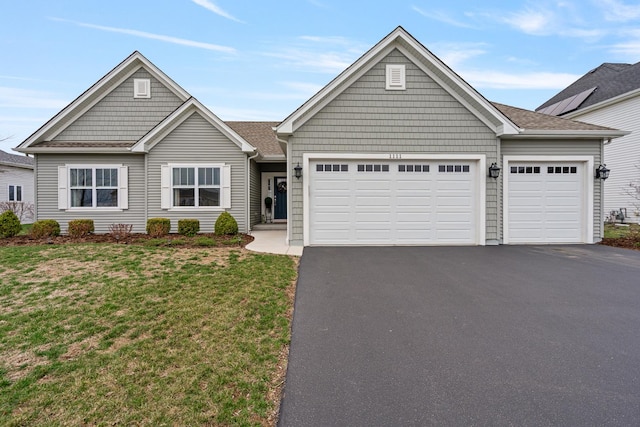 view of front facade with a front lawn, driveway, a garage, and roof with shingles