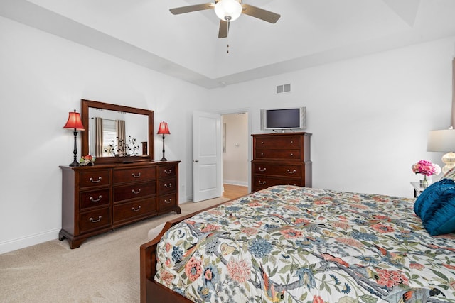 bedroom featuring baseboards, a tray ceiling, visible vents, and light carpet