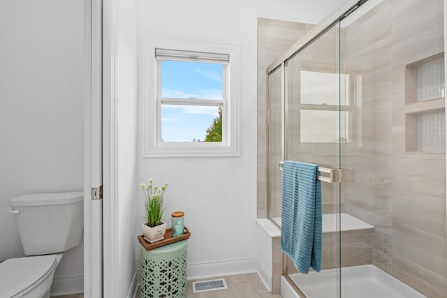 full bath featuring toilet, a shower stall, baseboards, and visible vents