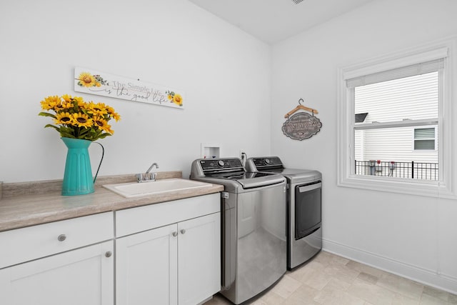 clothes washing area featuring baseboards, cabinet space, a sink, and washer and dryer
