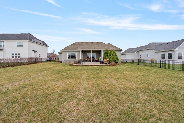 rear view of property featuring a patio, a lawn, and a fenced backyard