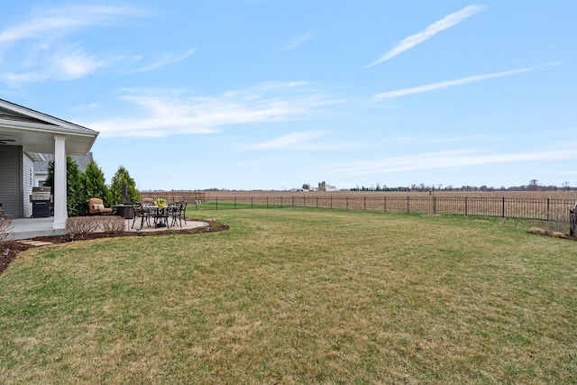 view of yard featuring a rural view, fence, and a patio