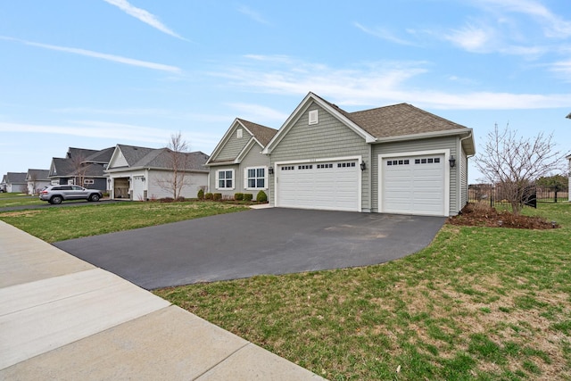view of front of house with an attached garage, aphalt driveway, roof with shingles, and a front yard