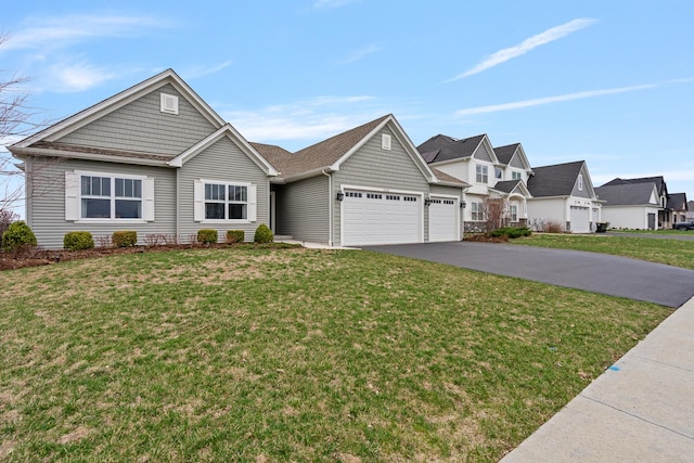 view of front of home with a front lawn, a residential view, a garage, and aphalt driveway
