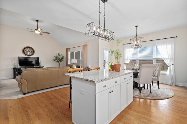 kitchen featuring open floor plan, light wood-style flooring, white cabinetry, and ceiling fan with notable chandelier