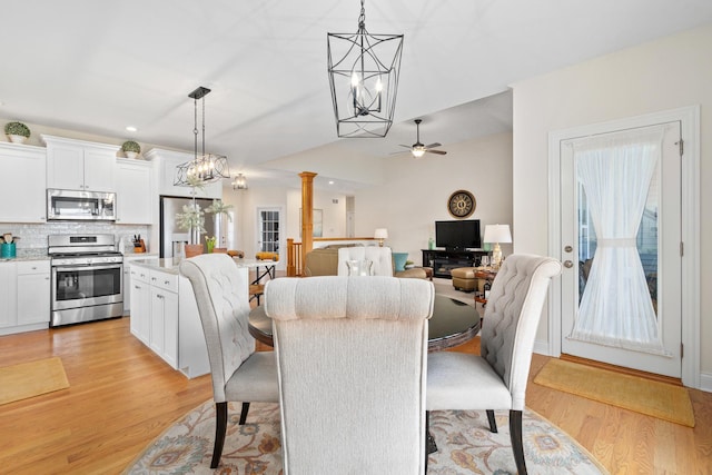 dining space featuring light wood-style floors, ceiling fan with notable chandelier, a healthy amount of sunlight, and ornate columns