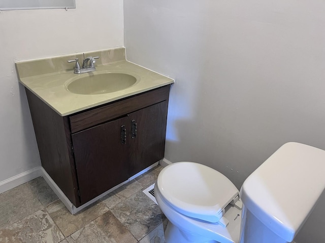 bathroom with baseboards, toilet, and vanity