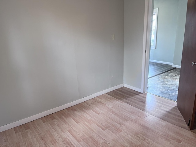 empty room with baseboards and light wood-type flooring