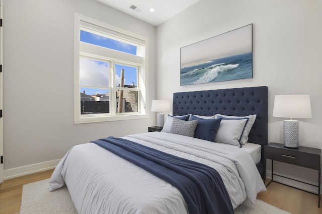 bedroom with baseboards, wood finished floors, visible vents, and recessed lighting