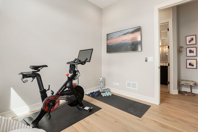 workout room with light wood-type flooring, baseboards, and visible vents