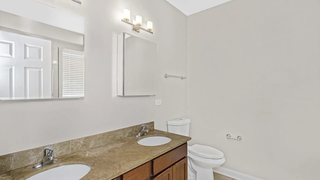 bathroom with double vanity, toilet, baseboards, and a sink