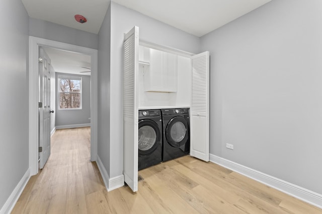 laundry room featuring baseboards, washing machine and dryer, light wood-style flooring, and laundry area