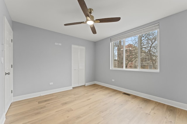 unfurnished bedroom with light wood-style flooring, a closet, baseboards, and visible vents