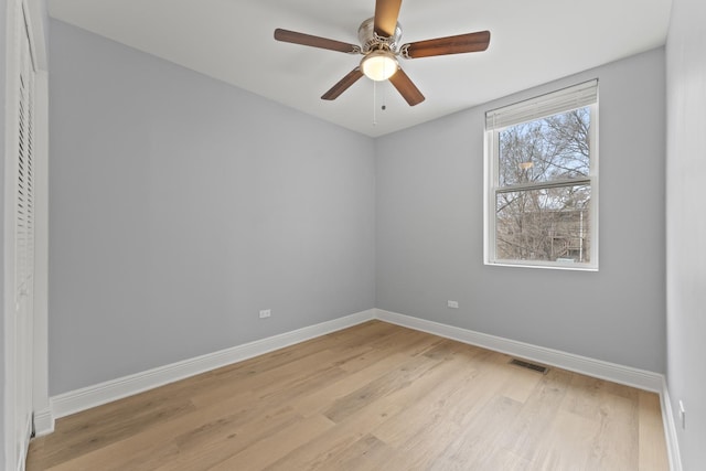 spare room with a ceiling fan, light wood-style flooring, baseboards, and visible vents
