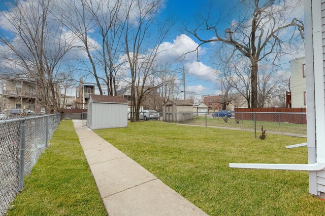 view of yard with a storage unit, a fenced backyard, and an outbuilding