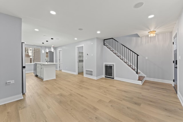 unfurnished living room featuring stairs, light wood-type flooring, recessed lighting, baseboards, and visible vents