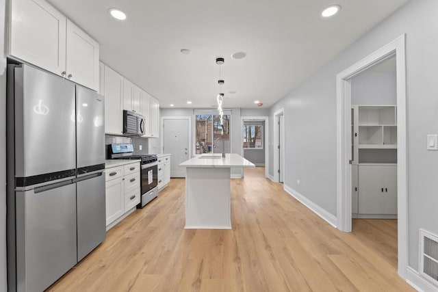 kitchen featuring white cabinets, light countertops, stainless steel appliances, a sink, and light wood-type flooring