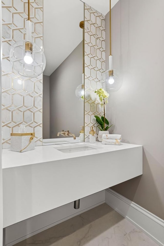 bathroom featuring marble finish floor, baseboards, vaulted ceiling, and vanity