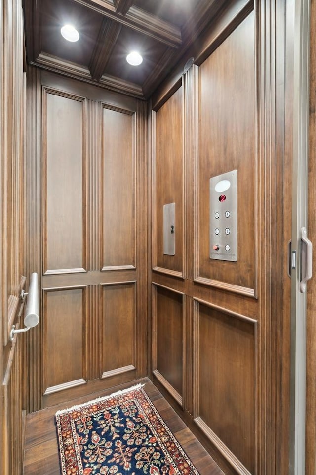 interior details with coffered ceiling, elevator, beamed ceiling, and wood finished floors