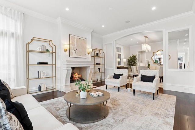 living room featuring recessed lighting, ornamental molding, baseboards, a lit fireplace, and dark wood finished floors