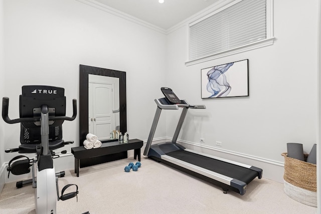 exercise area featuring baseboards, ornamental molding, and carpet