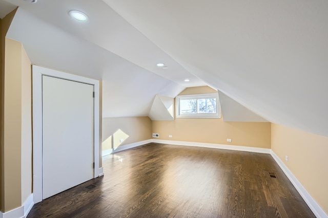 bonus room with lofted ceiling, dark wood-style floors, and visible vents