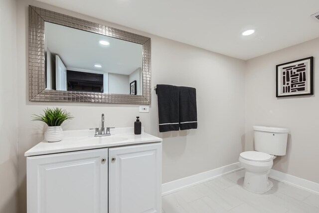 half bath with toilet, vanity, baseboards, visible vents, and recessed lighting