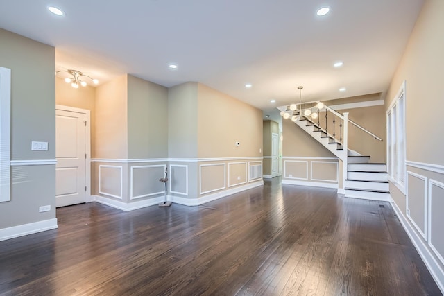unfurnished living room with recessed lighting, wood finished floors, a decorative wall, and stairway