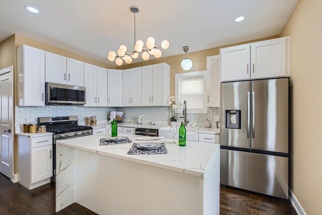 kitchen with dark wood finished floors, decorative backsplash, a sink, white cabinets, and appliances with stainless steel finishes