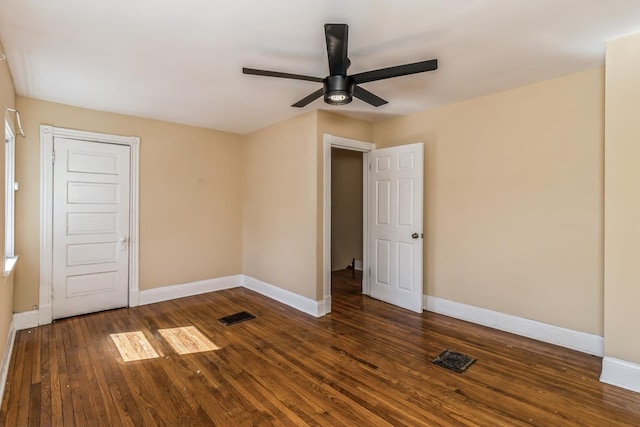 unfurnished room with baseboards, dark wood-style flooring, visible vents, and a ceiling fan