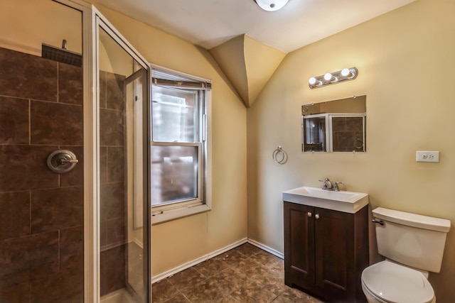 bathroom with vanity, toilet, plenty of natural light, baseboards, and a stall shower